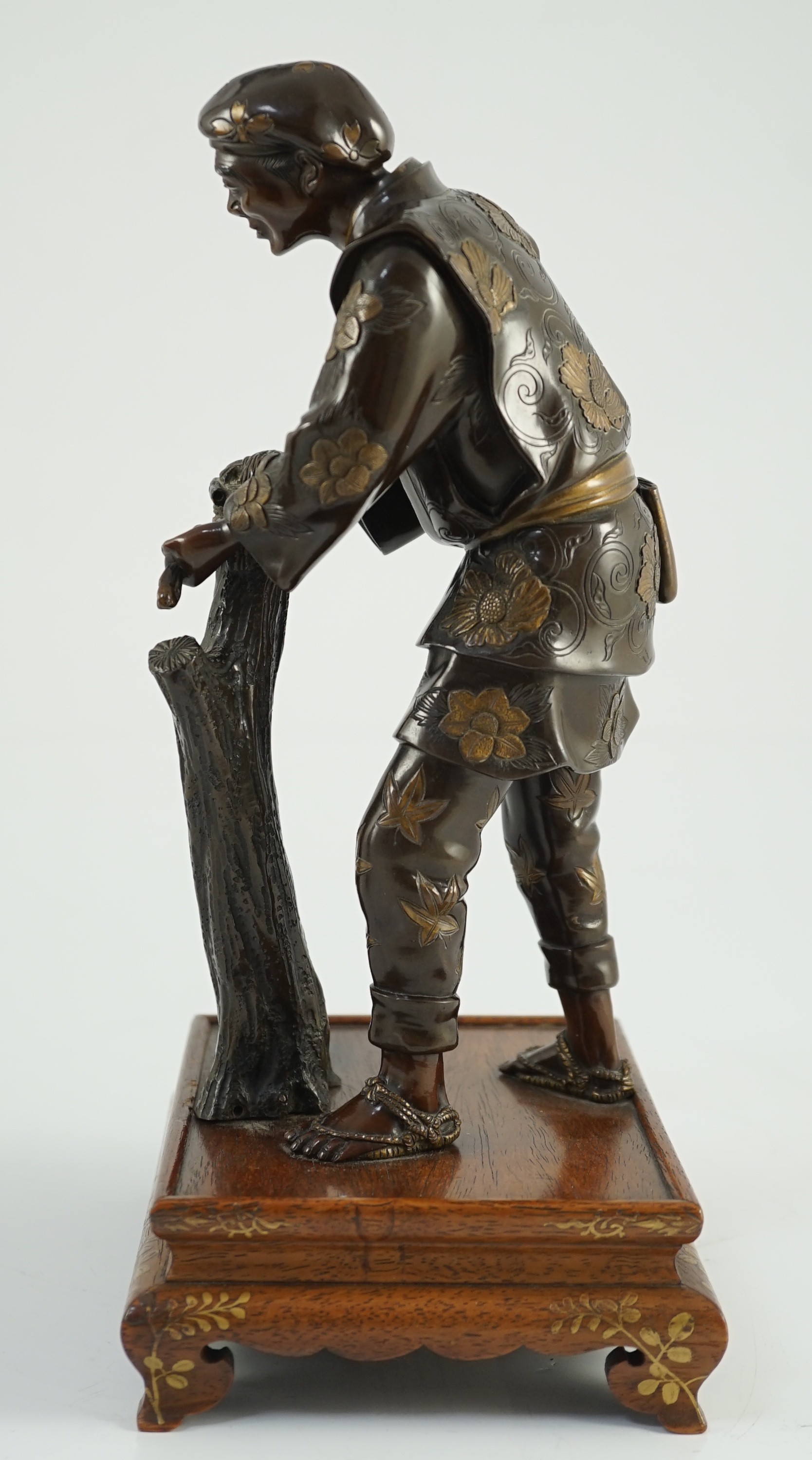 A Japanese brown patinated and gilded bronze figure of a woodworker, in Miyao style, Meiji period, 27.5cm high